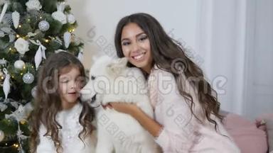 圣诞节的一家人，姐妹俩正坐在沙发上摆着相机，坐着一只白狗